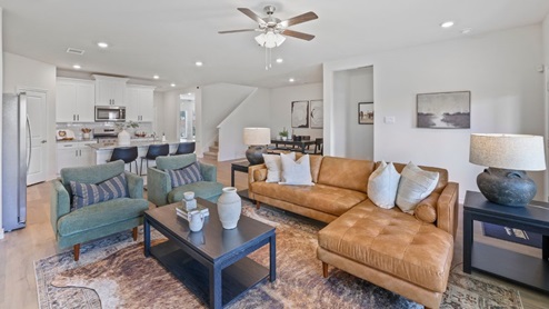 Spacious living room with brown flooring, white walls and windows