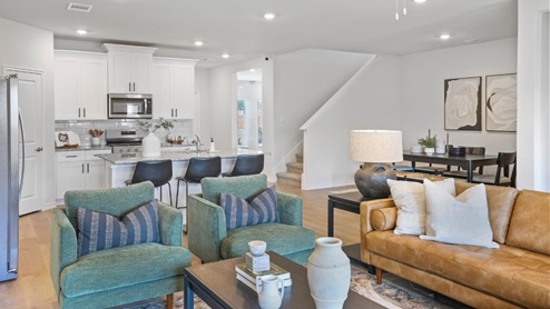 Spacious living room with brown flooring, white walls and windows