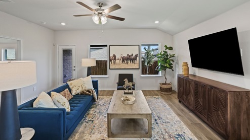 Spacious living room with brown flooring, white walls and windows