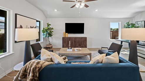 Spacious living room with brown flooring, white walls and windows