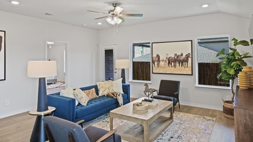 Spacious living room with brown flooring, white walls and windows