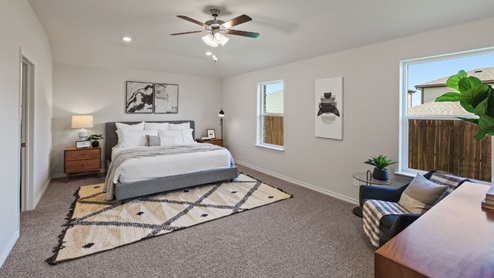 Spacious primary bedroom with beige carpet, white walls and two windows