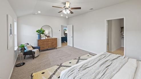 Spacious primary bedroom with beige carpet, white walls and two windows