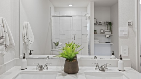 bathroom with dual vanity sinks, toilet, and a walk in shower