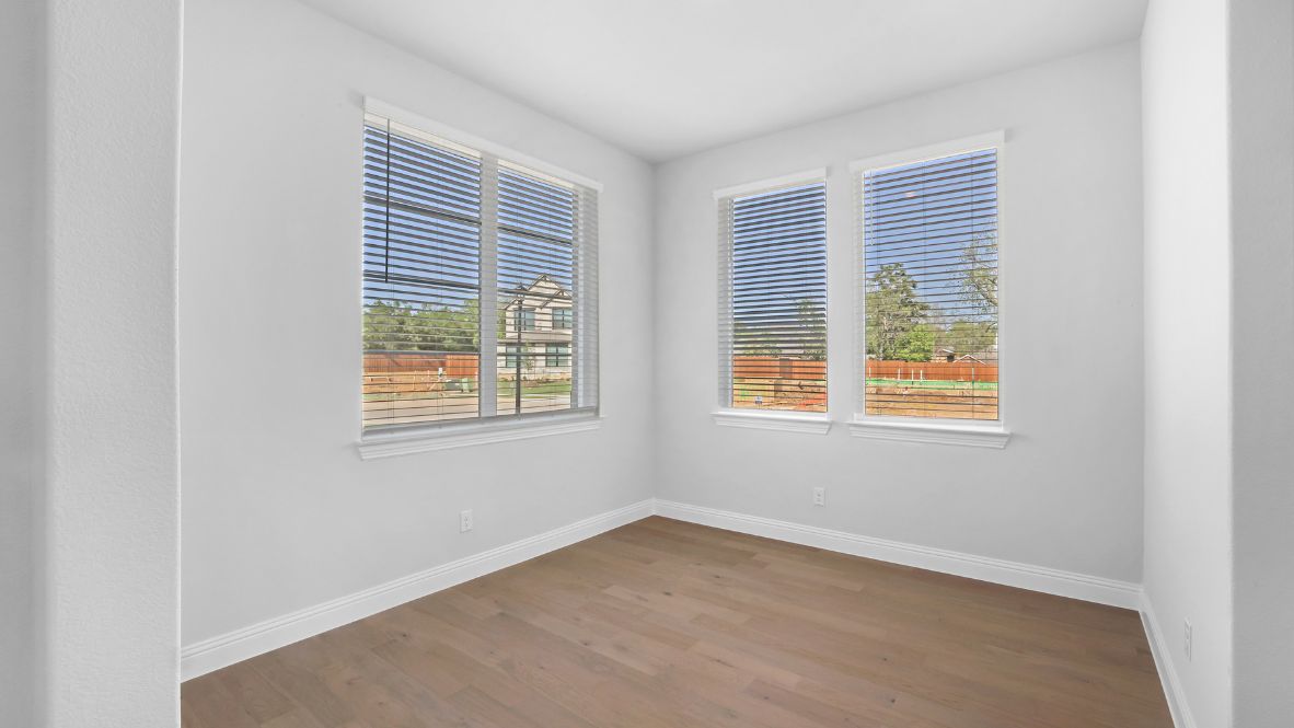 Dining area off the kitchen with light brown flooring and large windows.
