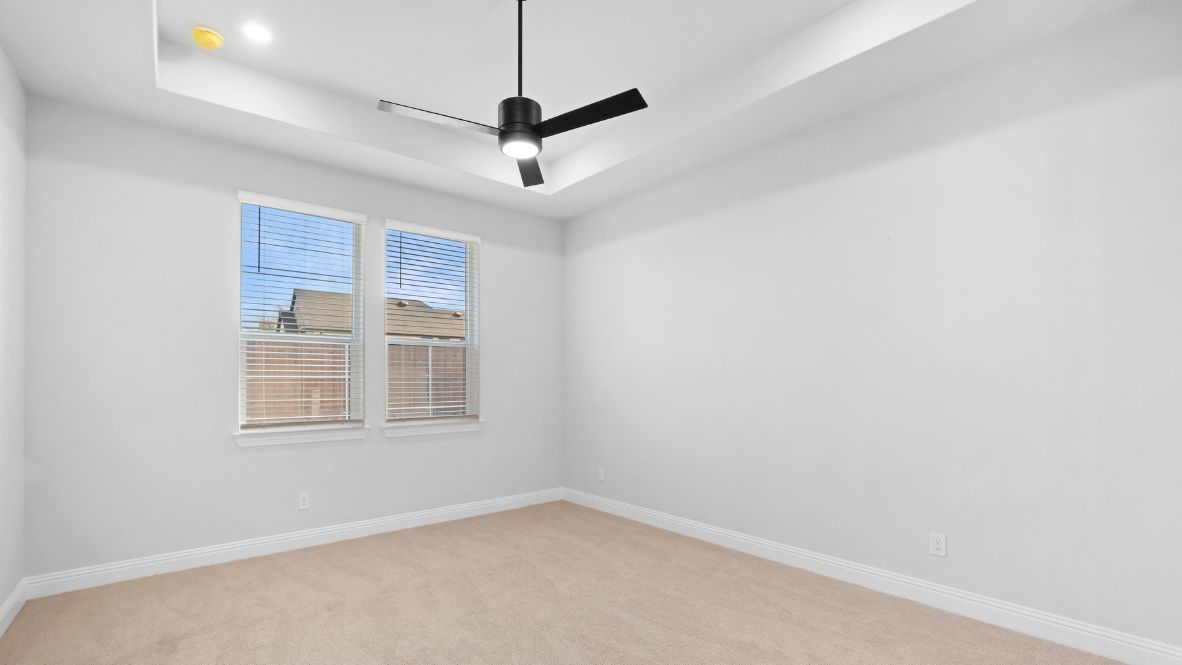 Bedroom with light brown carpet and windows.