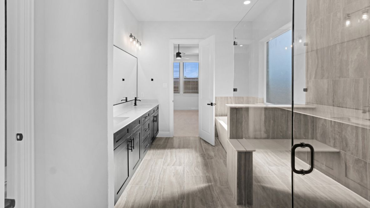 Bathroom featuring dual sinks, a walk in shower, and a standing tub.