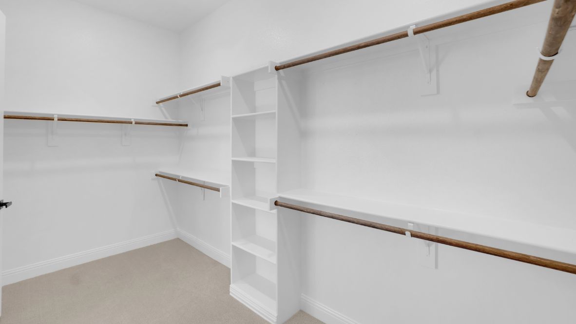 Walk in closet with built in shelving and hanging rods.
