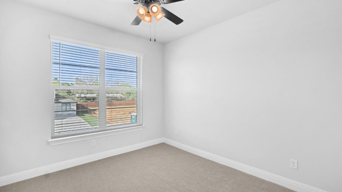 Bedroom with light brown carpet and windows.