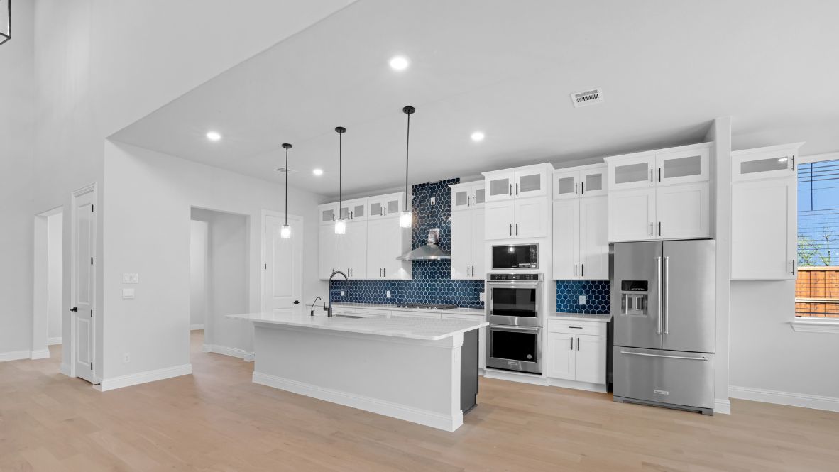 Kitchen featuring white cabinets, blue tile, and stainless steel appliances.