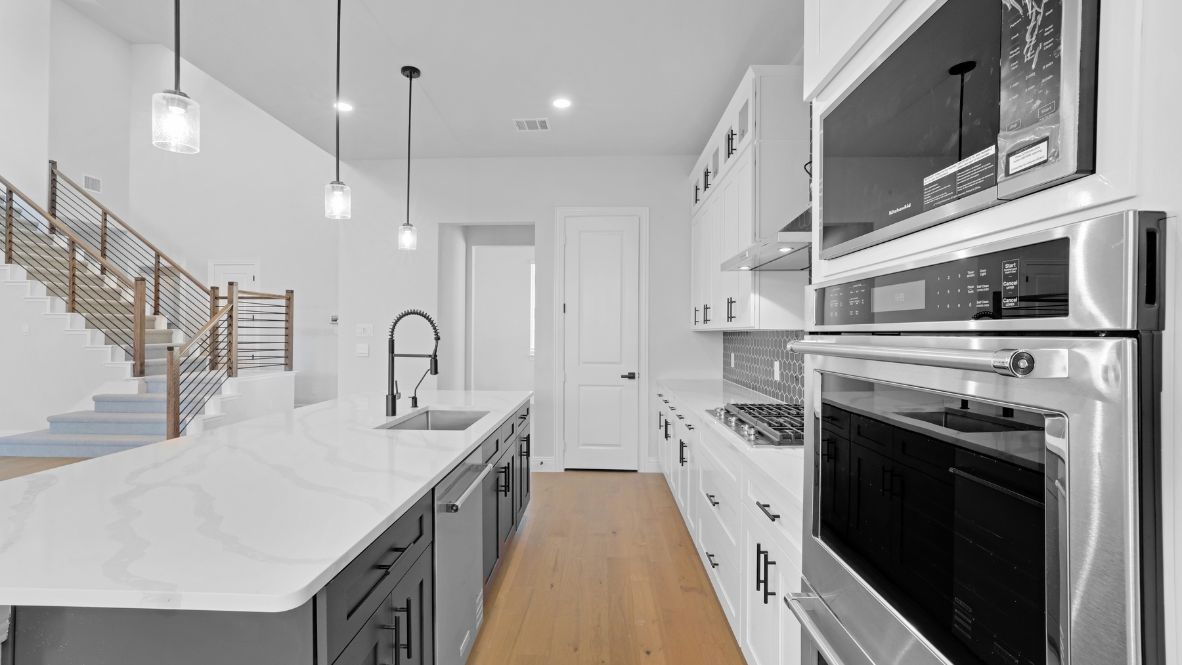 Kitchen featuring white cabinets, blue tile, and stainless steel appliances.