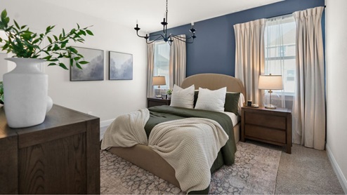 Interior primary bedroom with accent wall and windows