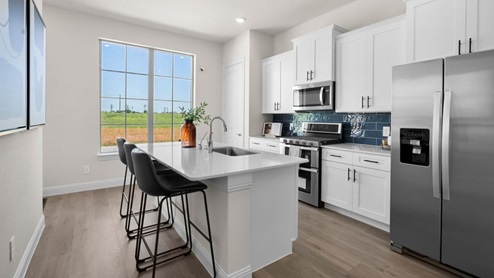 Interior kitchen with center island with white cabinets next to large window