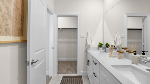 Interior primary bathroom with double sink, shower and walk-in closet
