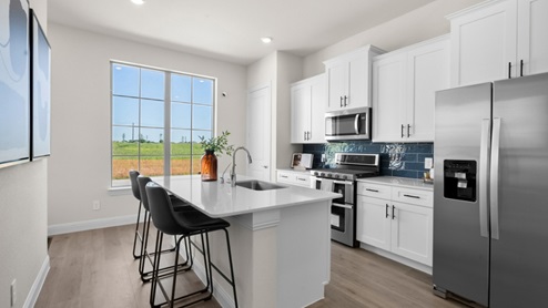 Interior kitchen with center island with white cabinets next to large window