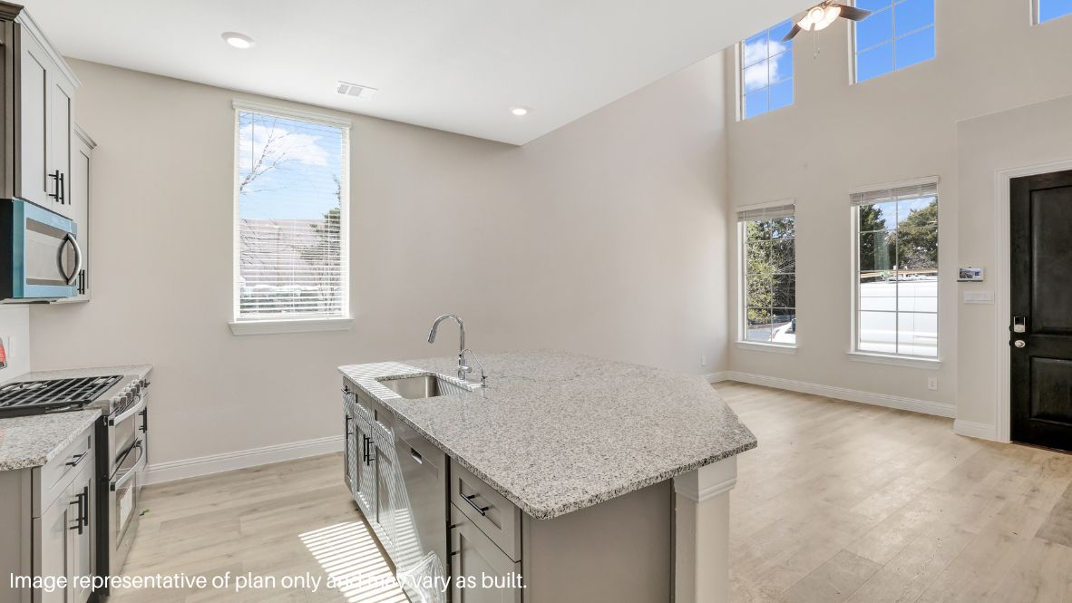 Inside, natural light floods the open-concept living space, highlighting the sleek picture-frame cabinetry, quartz or granite countertops, and stainless steel appliances in the chef-inspired kitchen.