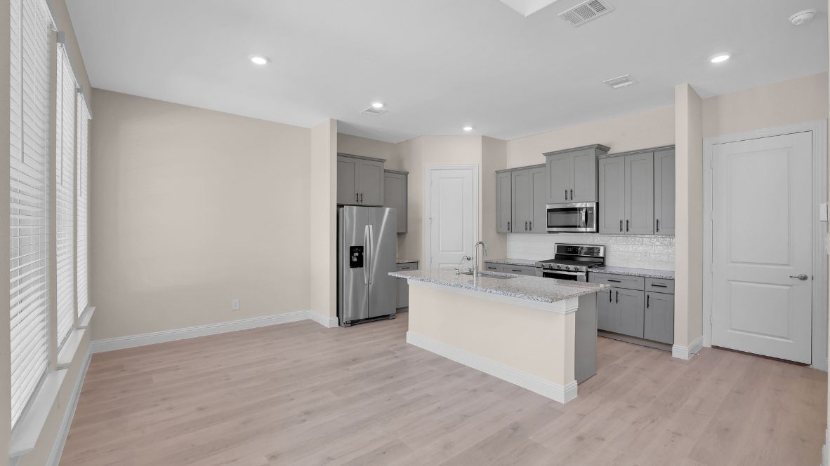 Spacious kitchen with hard surface flooring, pantry and island counterspace.