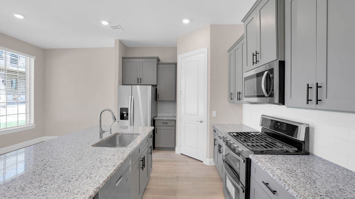 Spacious kitchen with hard surface flooring, pantry and island counterspace.