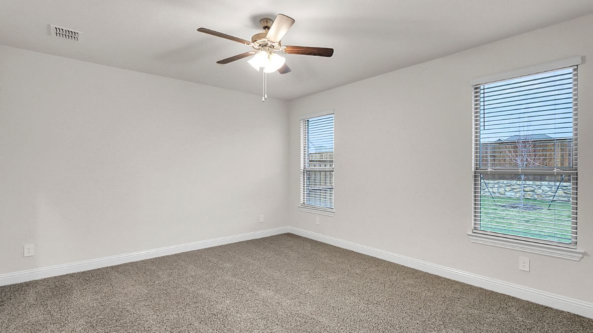Primary bedroom with ceiling fan, plush carpeting, and a large walk-in closet.