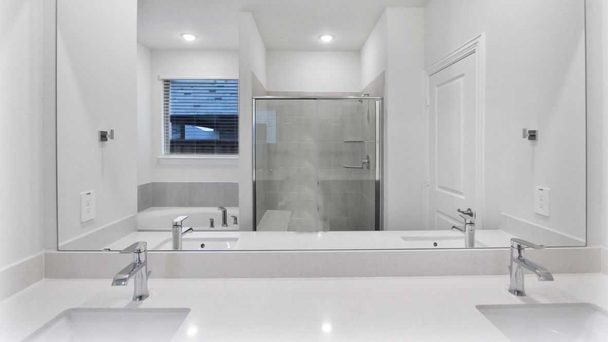 Spacious modern bathroom featuring a glass-enclosed shower, a large soaking tub with tiled surround and dual-sink vanity with sleek countertop. The layout includes a private water closet and a walk-in closet for added convenience, with natural light streaming through the window.
