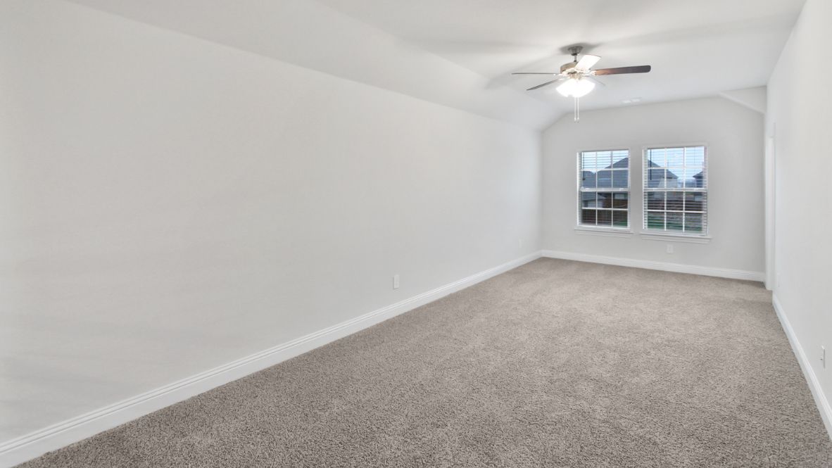 Bright and airy loft area with carpeted flooring, modern railing, and ceiling fan lighting. The open design overlooks the main living space below, creating a perfect spot for relaxation or additional living space.