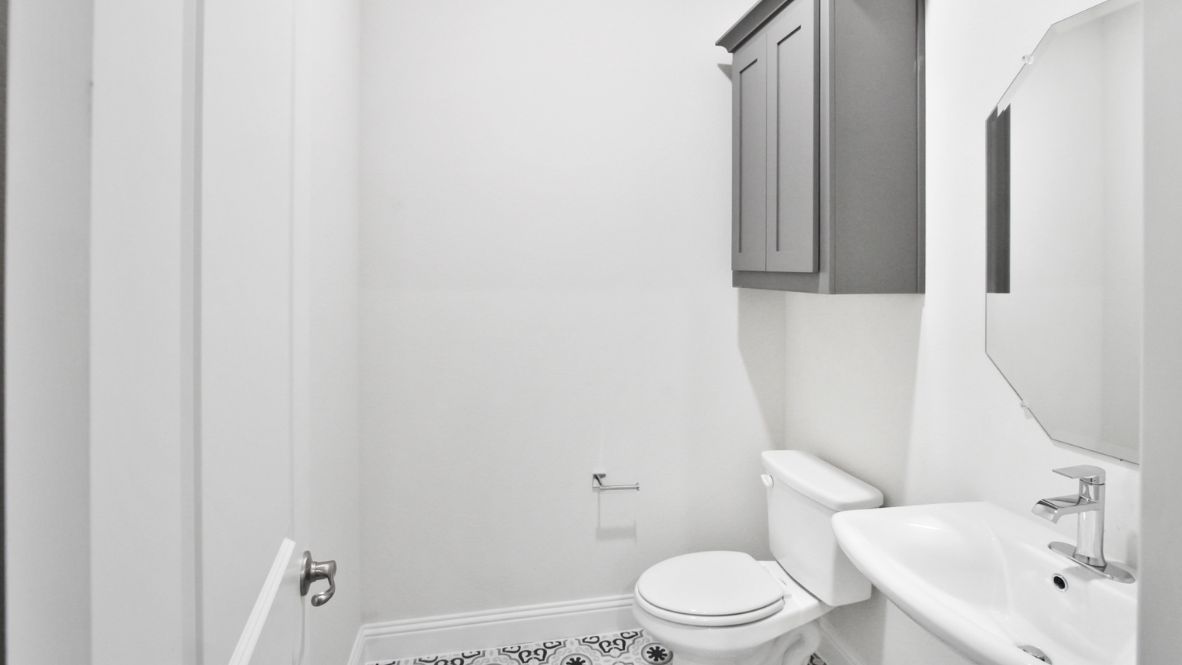 Modern secondary bathroom showcasing white cabinets, a sink, quartz countertops, and a 12x24 tiled shower surround.