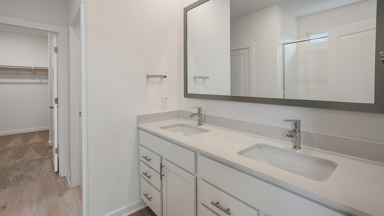 spacious bathroom with double vanities and white countertops