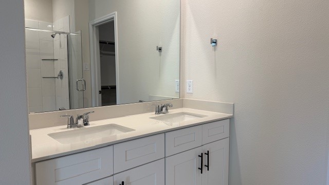 Modern primary bathroom with double vanities, granite countertops, and a glass-enclosed shower with a walk-in closet.