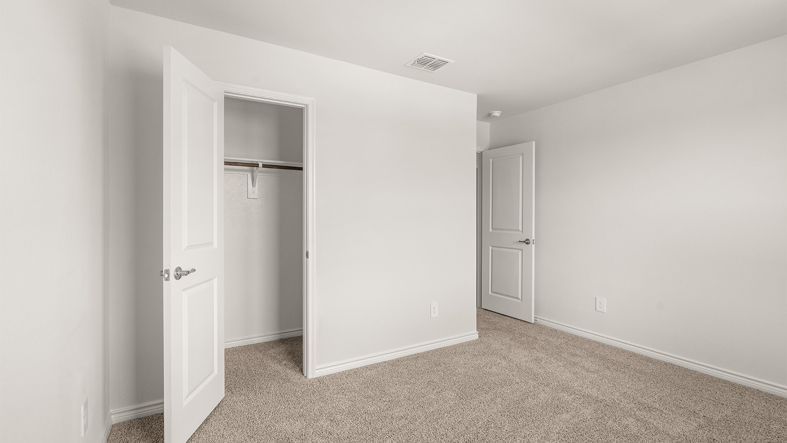 Primary bedroom with ceiling fan, plush carpeting, and a large walk-in closet.