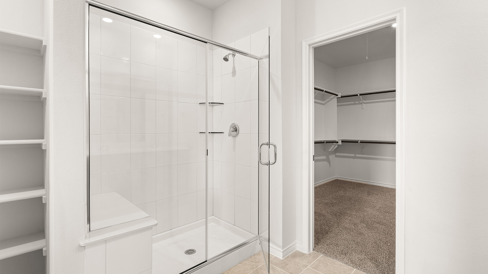 Modern primary bathroom with double vanities, granite countertops, and a glass-enclosed shower with a walk-in closet.