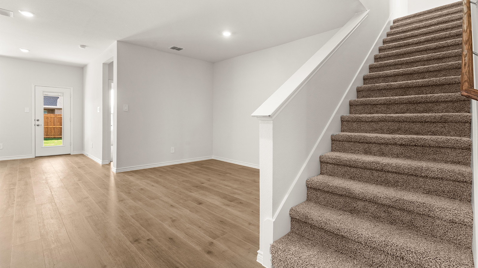 A cozy living room feature vinyl wood flooring and a view to the kitchen and dining area.