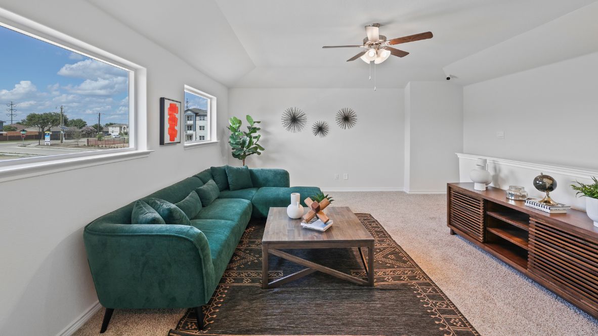 second story entertainment room with ceiling fan.