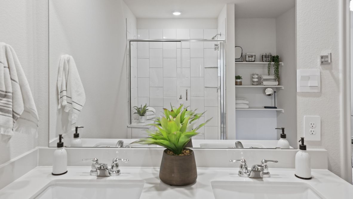 Luxurious primary bathroom with dual vanities, a soaking tub, glass-enclosed shower and walk-in closet.