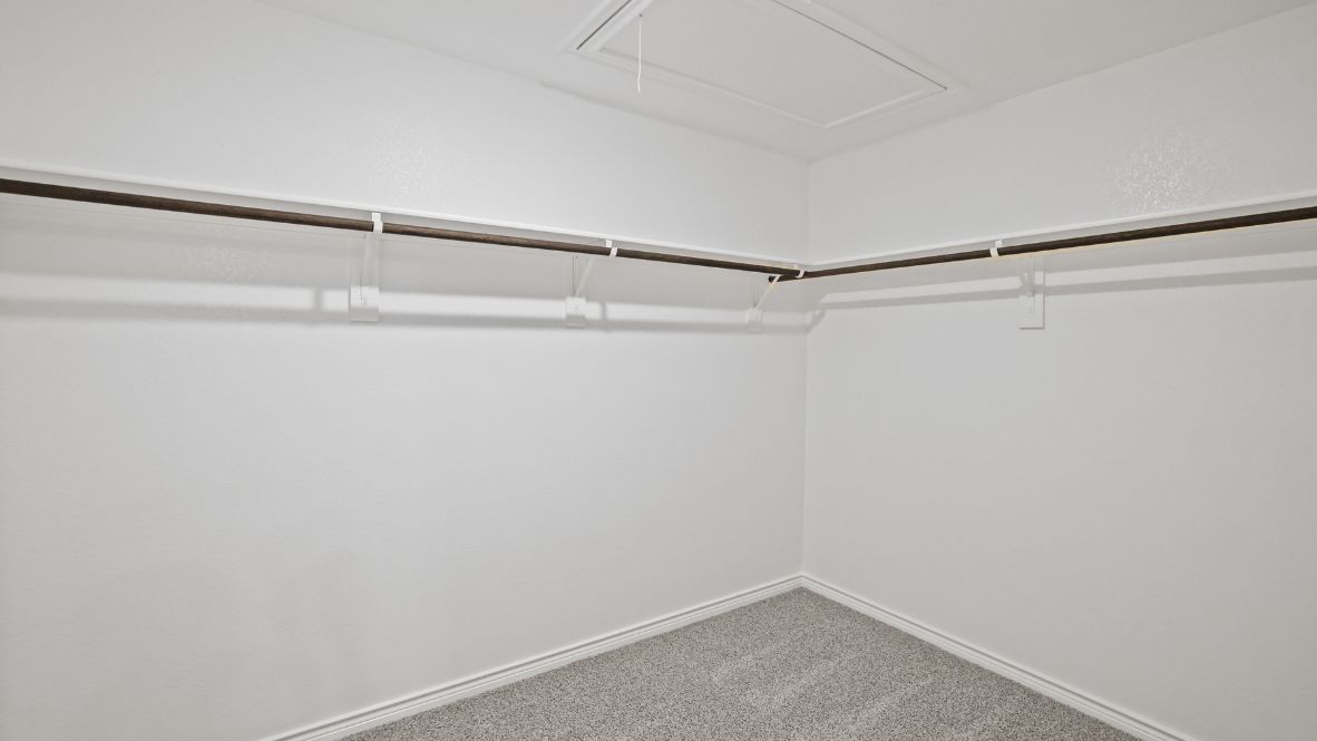 Walk in closet with rods and carpeted floors.