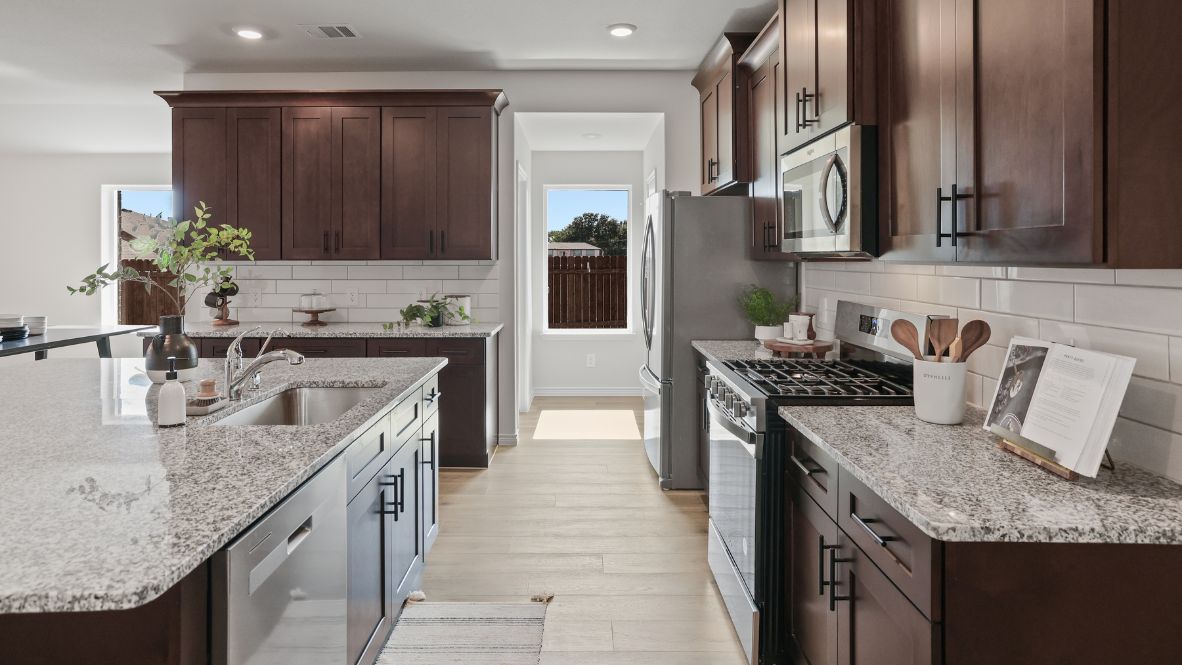 Spacious kitchen with granite tops, wooden cabinets, and stainless steel appliances.