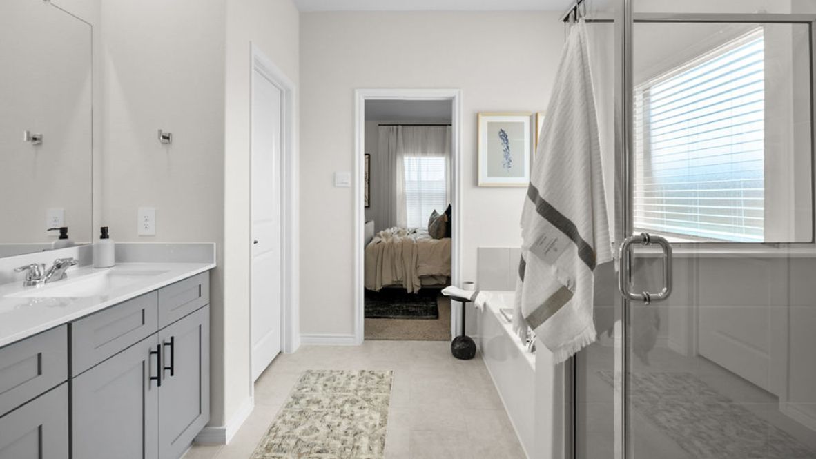 Luxurious primary bathroom with dual vanities, a soaking tub, glass-enclosed shower