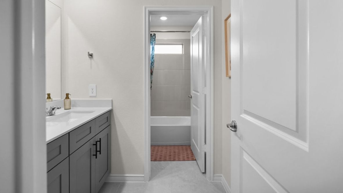 Modern secondary bathroom showcasing white cabinets, a sink, and quartz countertops.