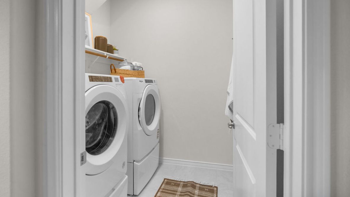 A laundry room featuring a washer and dryer, neatly arranged with ample space for laundry tasks and storage.