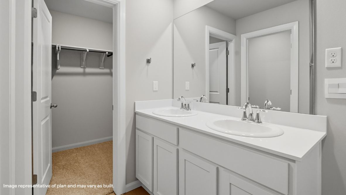 Modern primary bathroom with double vanities, quartz countertops, and a glass-enclosed shower with a walk-in closet.