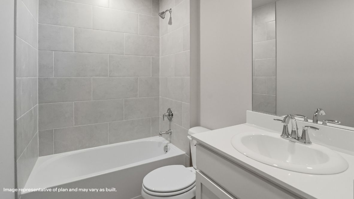 Modern secondary bathroom showcasing white cabinets, a sink, quartz countertops, and a 12x24 tiled shower surround.