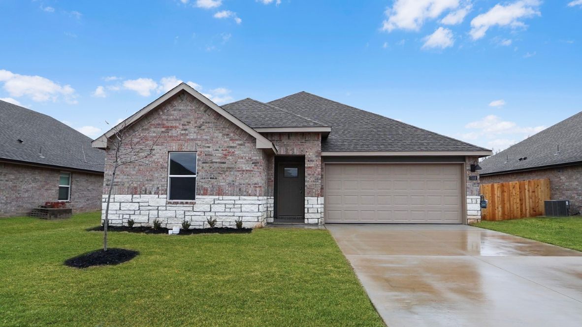 Exterior from sidewalk view of grass and front of new house Conrad Village