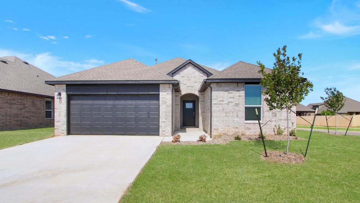Modern single-story home with a brick exterior, two-car garage, and well-maintained front lawn in a suburban neighborhood