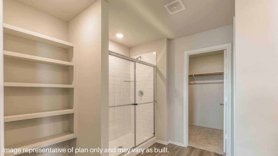 Primary bedroom with plush carpeting, and a large walk-in closet.