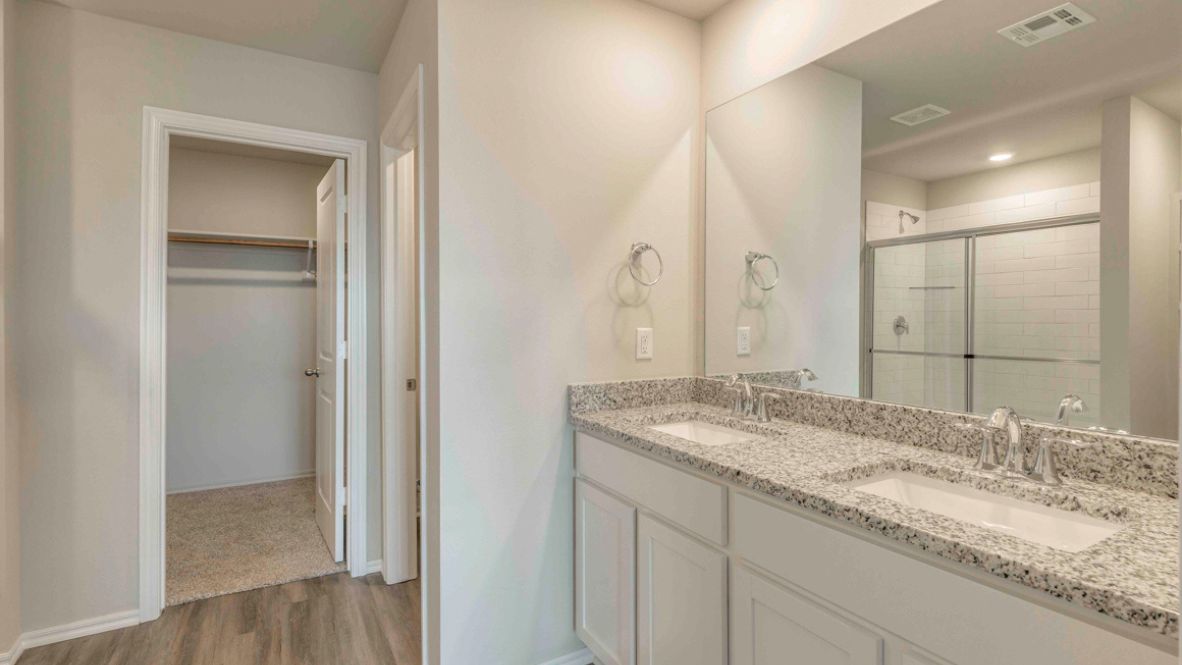 Primary bedroom with plush carpeting, and a large walk-in closet.