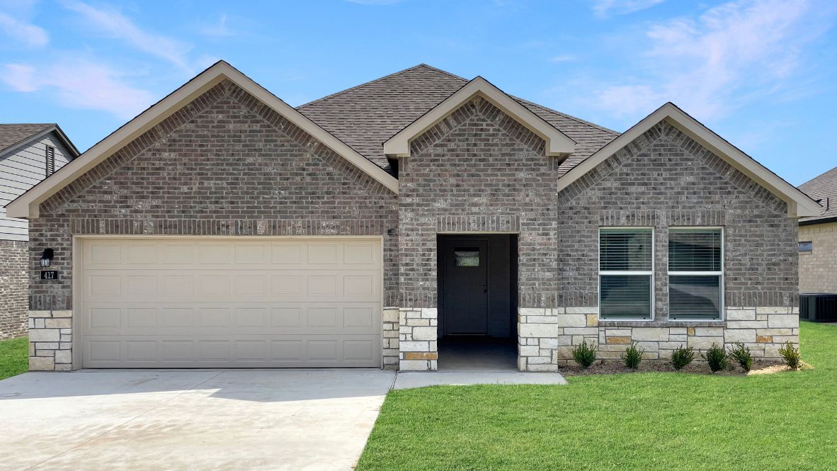 Modern single-story home with a brick exterior, two-car garage, and well-maintained front lawn in a suburban neighborhood