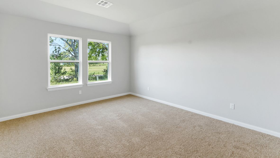Primary bedroom with ceiling fan, plush carpeting, and a large walk-in closet.