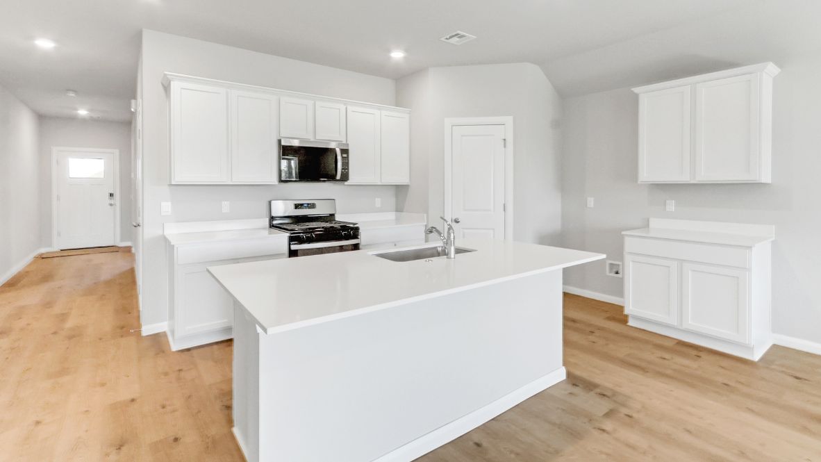 Bright and spacious kitchen with quartz countertops, stainless steel appliances, and an island with bar seating.