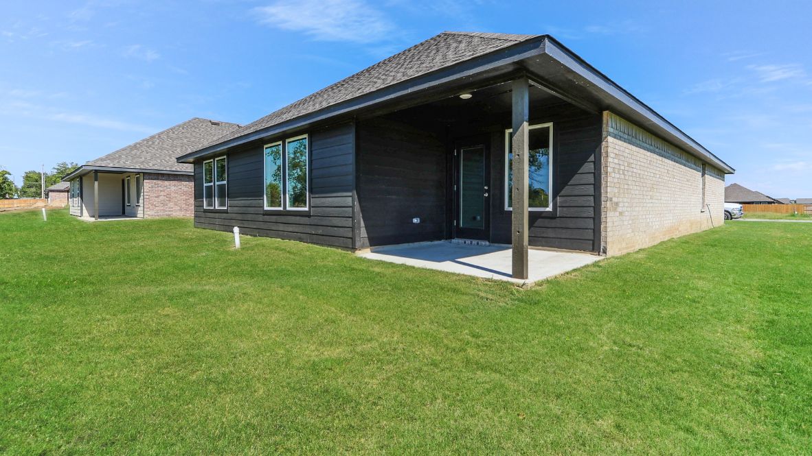 Outdoor covered patio with seating area overlooking a well-maintained lawn, perfect for relaxation.