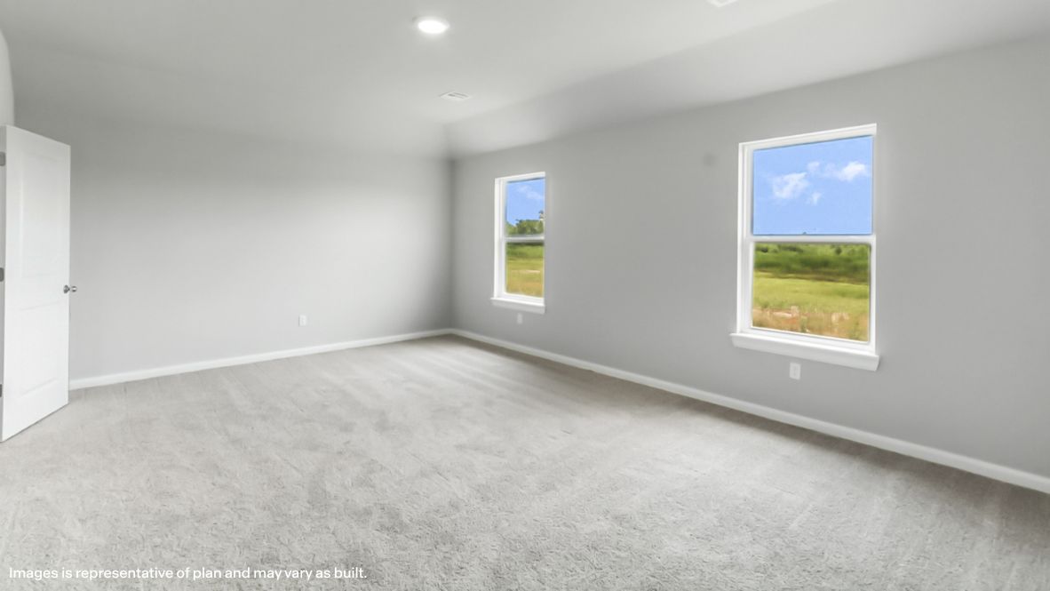 Primary bedroom with ceiling fan, plush carpeting, and a large walk-in closet.
