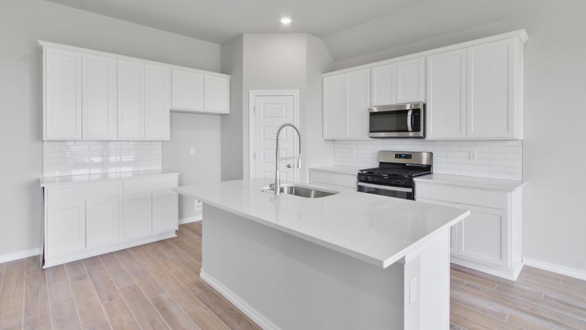 Bright and spacious kitchen with quartz countertops, stainless steel appliances, and an island with bar seating.